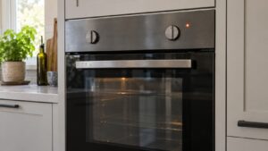 A built-in wall oven with a glowing indicator light on its panel while the control knob is turned to the off position